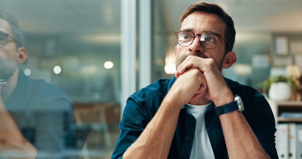 A man sitting with his hands clasped, thinking