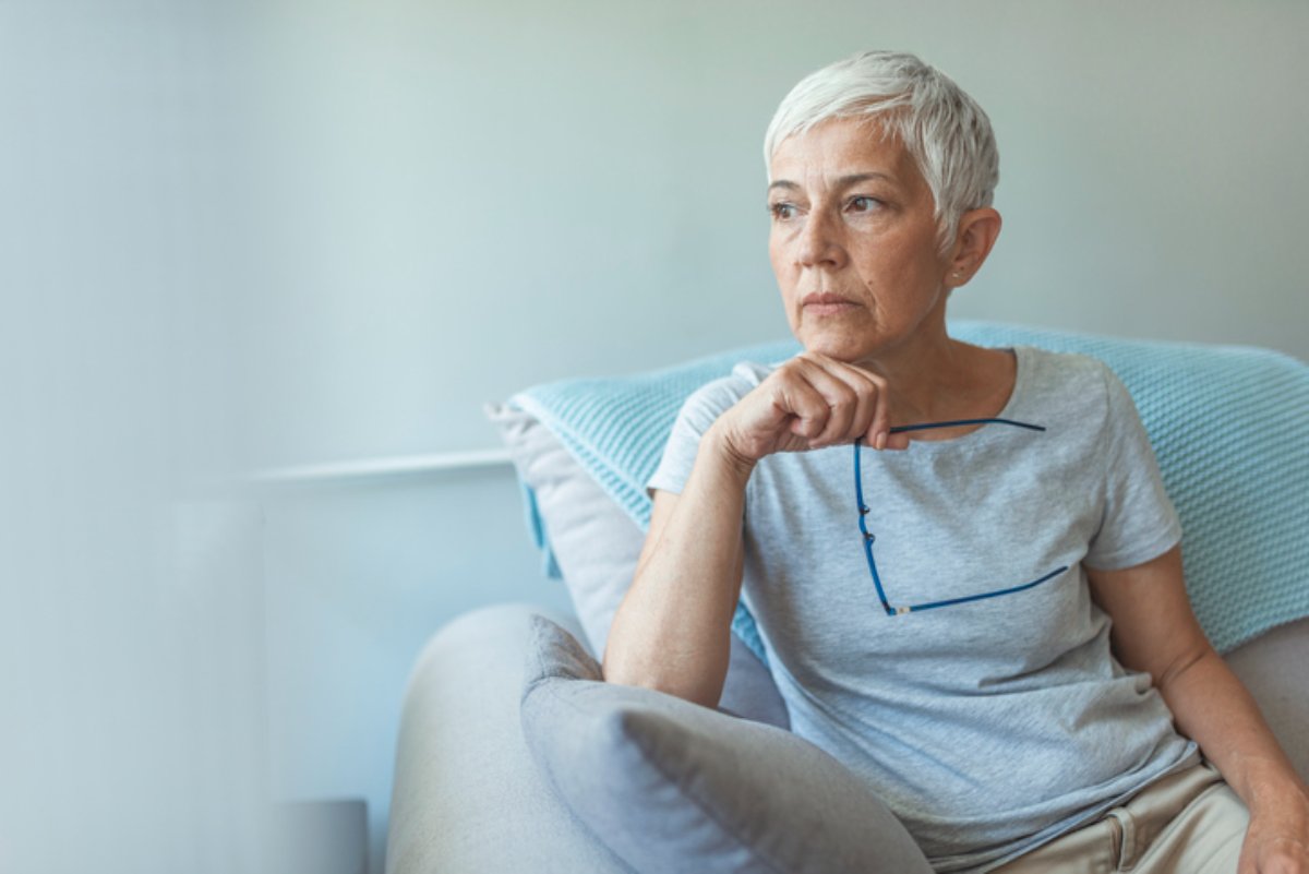 A woman sitting at home, looking away in thought
